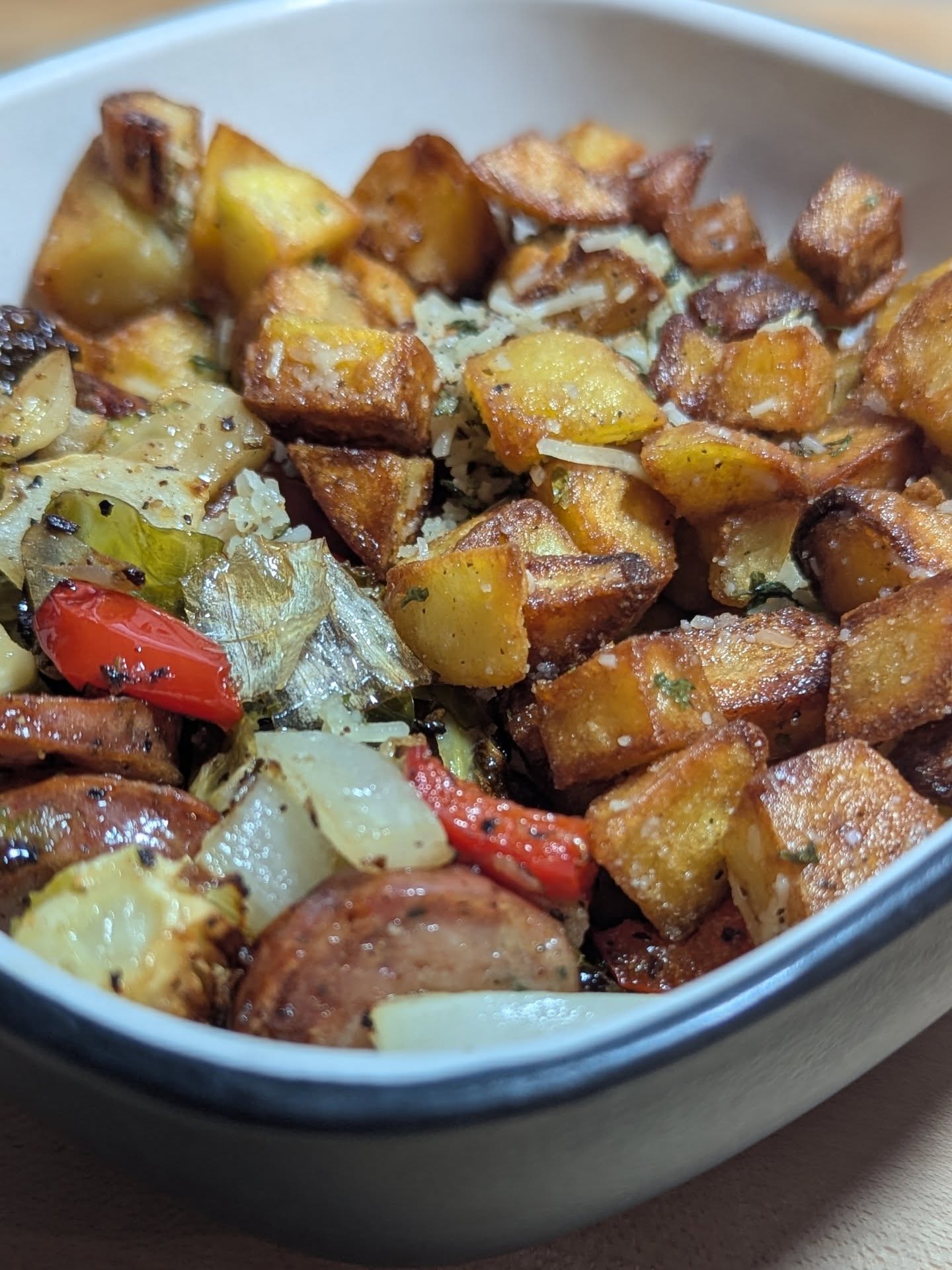 Sheet pan dinner with a side of crispy fried potatoes On the sheet pan is sausage, bell pepper. Onion and Brussels. Baked till crispy (45 min at 375,tossing at 15 min increments). Seasoned with @neilsarap tasty bark and olive oil.The potatoes were cubed and fried. Then tossed in parmesan, parsley and butter garlic seasoning from @boarsnightout