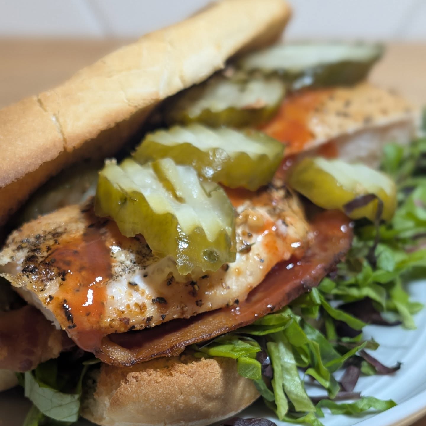 Buffalo Chicken Sandwich I enjoyed the prep of this one, focusing on refinement of every ingredient to build an amazing flavor profile. Starting with boneless skinless chicken breast seasoned with @spiceology buffalo lemon pepper and smoked with @bearmountainbbq gourmet blend at 225 for a laid on heavy smoke, but with amazing balance. I smoked all the way through so the chicken gets almost the feeling of a 'skin' to it. Packed with perfect sweet smokey flavor. The bacon was over cooked to a perfect crisp. This is home cured bacon, no sugar. I stacked mixed greens and gave them a julien cut for perfectly shredded lettuce. @grillospickles chips and a splash of @franksredhot finish up the prep. I toasted the sourdough roll, and started with a base layer of @litehousefoods buttermilk ranch. Then layered all my prepped ingredients. Lettuce, bacon, Chicken and pickles. #chickensandwich #bearmountianbbq